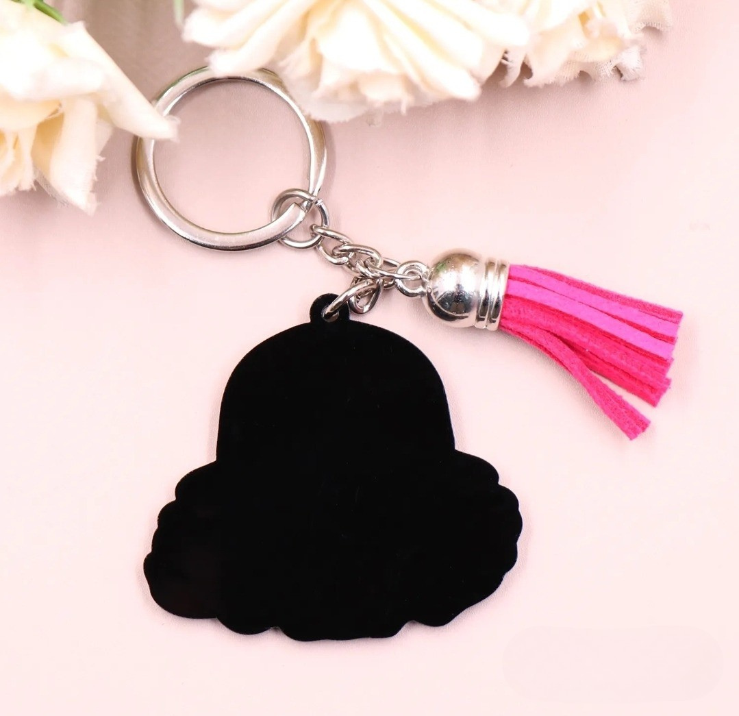 Back of Queen Energy keychain with pink tassel on a light pink background